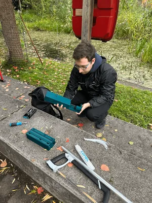 Ein Mann sitzt am Teich mit verschiedenen Sensorteilen in der Hand