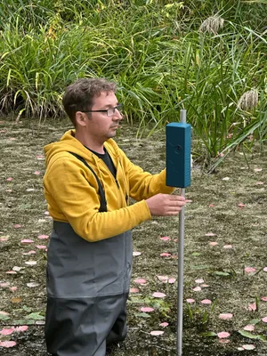 Ein Mann hält eine Stange im Wasser, an dem ein Sensor befestigt ist