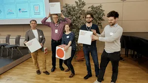 4 Männer und eine Frau posieren mit Würfeln für ein Gruppenbild
