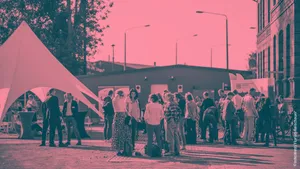 Gruppe von Menschen steht und unterhält sich im Freien vor einem Zelt und einem Gebäude