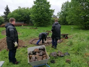 Mehrere Männer die im Garten arbeiten.
