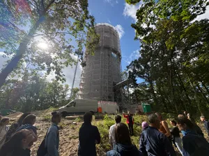Eine Gruppe Menschen vor einem Wasserturm im Baugerüst