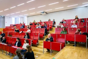 Menschen in einem Hörsaal mit roten Stühlen