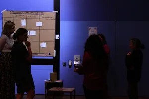Zu sehen ist ein dunkler Raum, mit etwas Licht auf einem Brown-Paper an der Wand