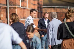 Vor dem Backsteingebäude des Transferortes begrüßen InNoWest-Mitarbeiter*innen und Besucher sich gegenseitig.