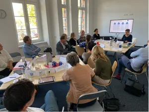Teilnehmende des Fachworkshops sitzen in einem Raum des Transferortes.
