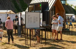Menschen stehen um einen Tisch mit einem Plakat darauf und diskutieren angeregt. 
