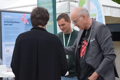 Drei Personen unterhalten sich am Stand "Einfamilienhaus - Was nun?" von InNoWest.