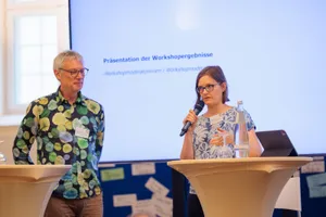 Die Sprecher*innen Dr. Josephine Jahn und Prof. Dr. Benjamin Nölting stehen am Mikrophon.