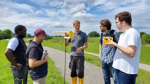 5 Männer stehen in der Natur, einer von Ihnen hält eine Stange, einer einen Sensor in der Hand