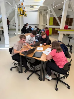 Schüler*innen arbeiten an Laptops in einem Klassenzimmer, konzentriert auf ihre Aufgaben.  
