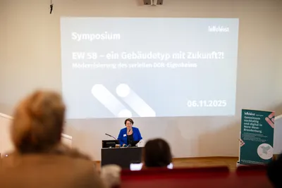 Eine Frau hält eine Präsentation vor einem großen Publikum.  