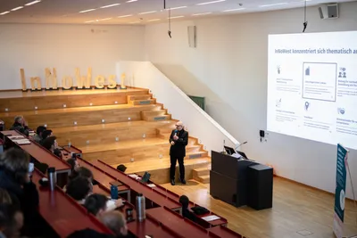 Ein Mann hält eine Präsentation vor einem großen Publikum.  