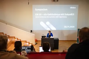 Eine Frau steht am Podium und gibt eine Präsentation in einem Vorlesungssaal.