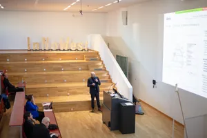 Ein Mann hält eine Präsentation vor einem Publikum im Vorlesungssaal. Im Hintergrund sind Holzbuchstaben mit den Lettern InNoWest zu sehen.