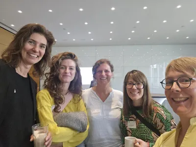 Auf dem Bild sind 5 Menschen zu sehen, die in die Kamera lächeln