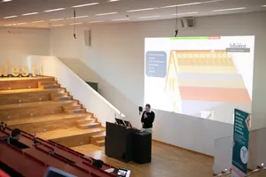 Ein Mann steht an einem Rednerpult und spricht in ein Mikrofon