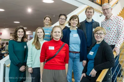 Neun Menschen stehen auf einer Treppfe und schauen in die Kamera