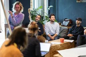 Ein Gruppe von Menschen diskutiert vor einem Flipchart