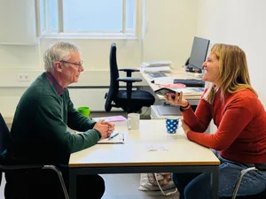 Zwei Menschen sitzen in einer informellen Interview-Situation in einem Büro