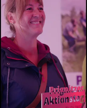 Aniko Herms-Neumann steht mit einer Hinweistafel in der Hand.