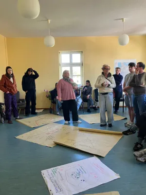 Viele Menschen stehen in einem Seminarraum und schauen Poster an