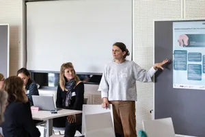 Eine Frau erklärt anhand eines Posters mehreren Menschen etwas