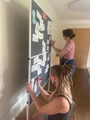 Laura van Altena und Andrea Prytula pinnen Karten an die Pinnwand.