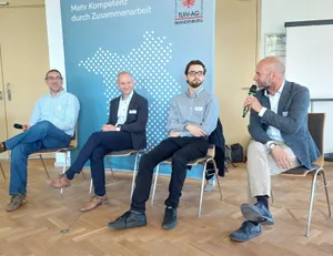 Vier Männer sitzen auf dem Podium der TUIV Konferenz 2025
