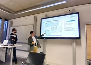 Zwei Personen stehen vor einer Leinwand und geben einen Input