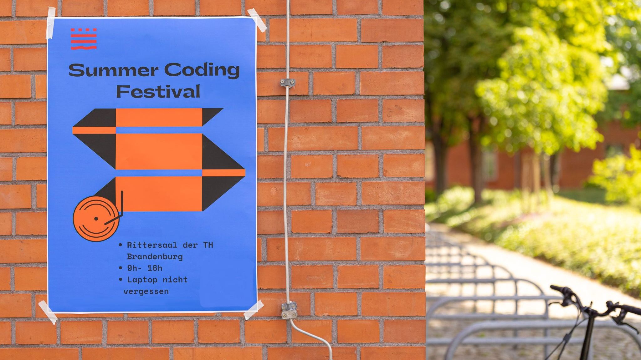 Plakat des Summer Coding Festivals an einer Mauer